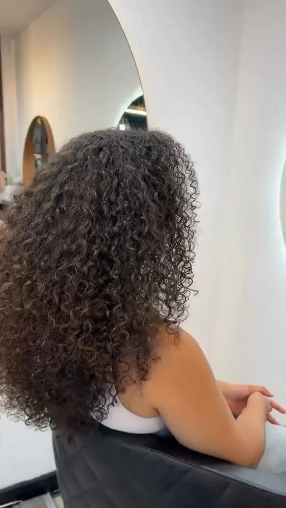 Lang, krullend haar voor de ronde spiegel in de salon, een still uit onze eigen film
