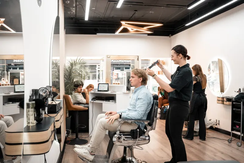 Een stylist aan het werk bij een klant in de witte salon