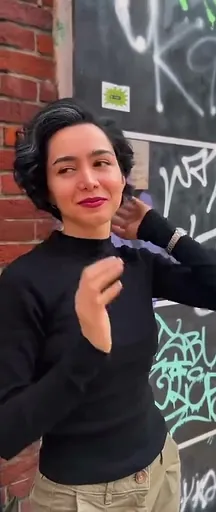 Kort, donker kapsel met golven, buiten tegen een muur met graffiti
