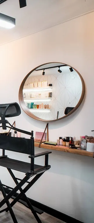 Een ronde spiegel met houten rand en een regisseursstoel in de witte salon