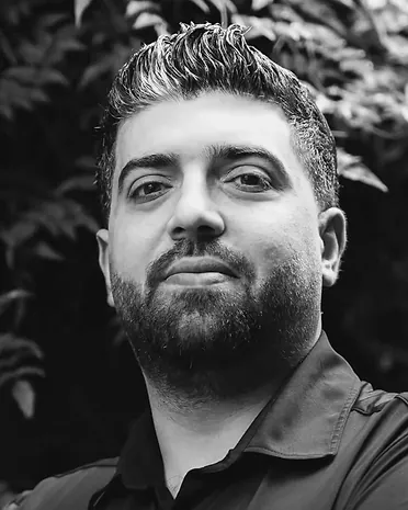 Zedan, met baard, voor een groene haag